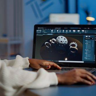 Tired african designer engineer analyzing new prototype of 3D model of industry product, working overtime. Industrial female worker studying gears idea on laptop showing cad software on device display